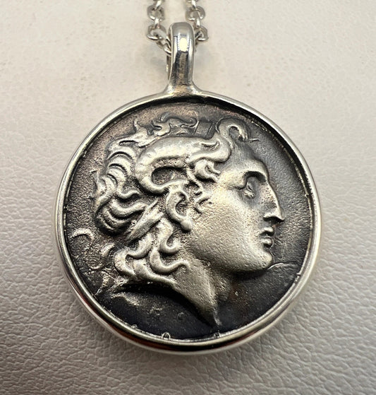 Silver pendant with a face design on a light gray background