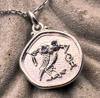 Silver pendant with a bird design on a textured surface