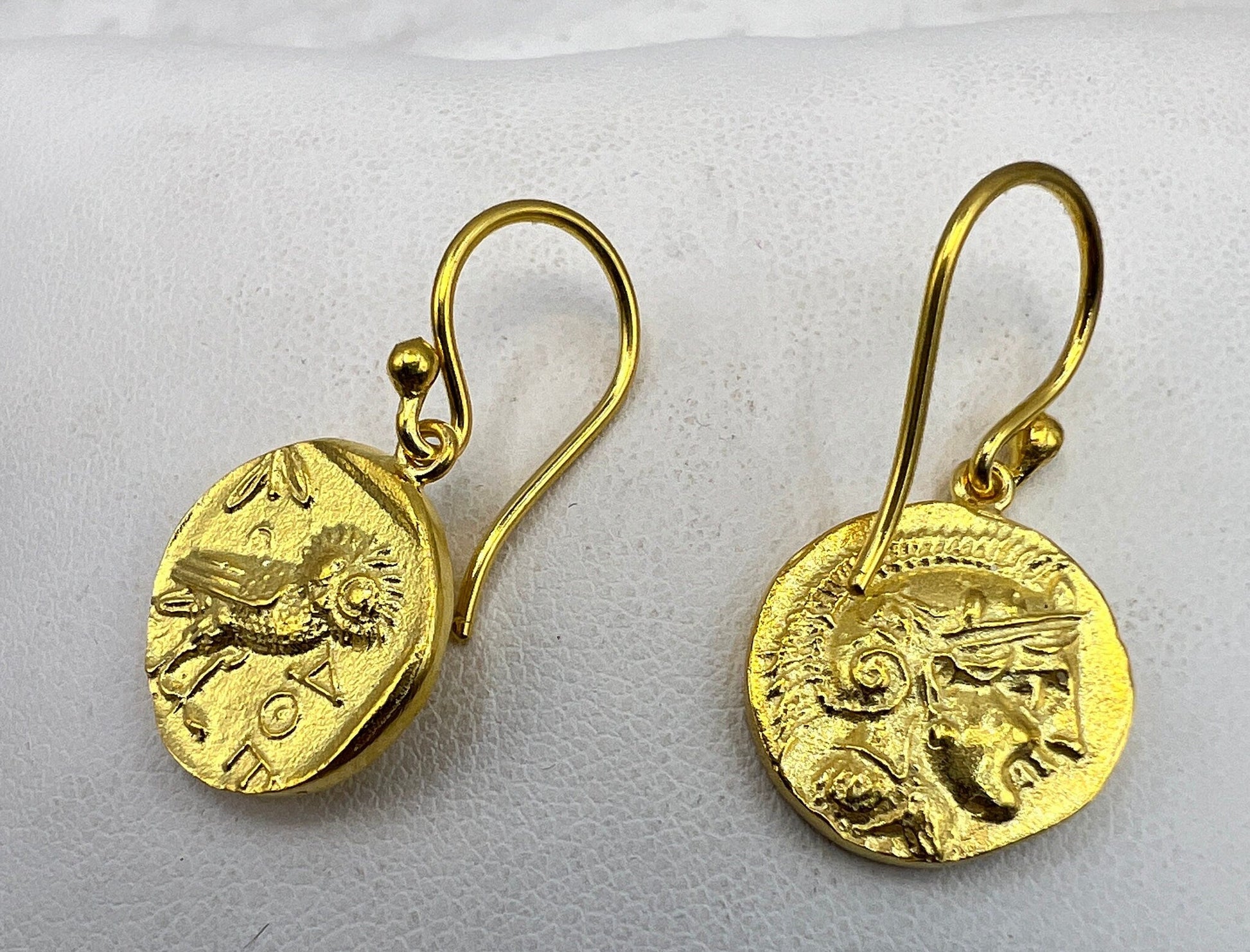Gold coin-shaped earrings on a light gray background
