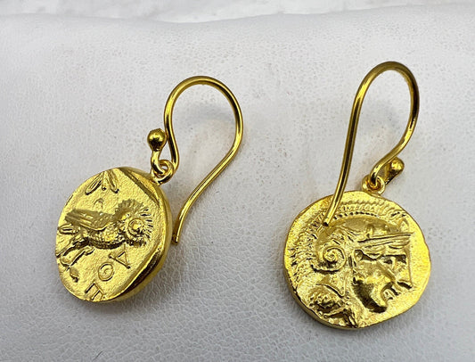 Gold coin-shaped earrings on a light gray background